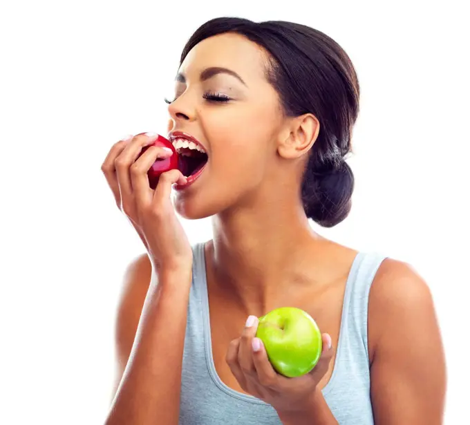 Tasty and healthy. Studio shot of a young woman in gymwear biting into an apple.