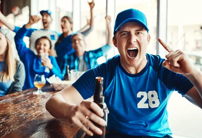 Our team will remain undefeated. Portrait of a man holding up one finger while watching a sports game with friends at a bar.