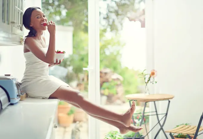 Enjoying a healthy and delicious snack. A young woman eating strawberries.