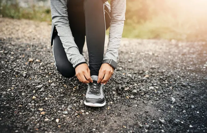 Closeup, fitness and woman outdoor, tie shoes and cardio workout for training, run and exercise. Zoom, female person or athlete start with practice, hands and runner outside for a marathon and sports