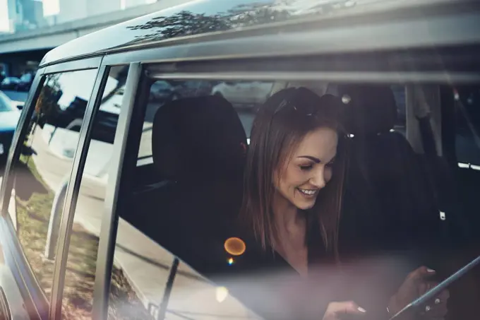 Work begins before she gets to the office. a young businesswoman using a digital tablet while traveling in a car.