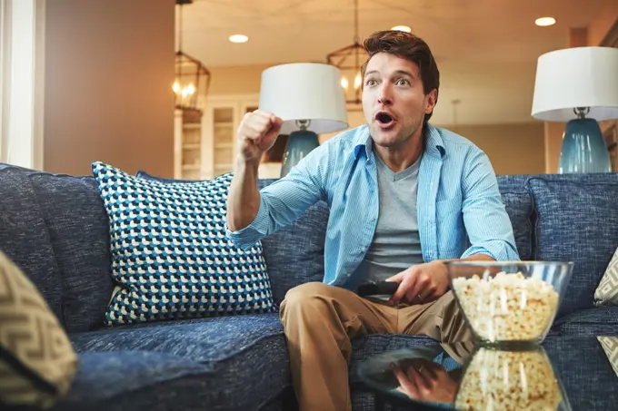 Real sports fans watch the game in real time. a young man watching an exciting sports match on tv.