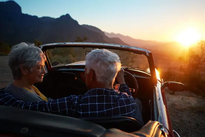 In love with each other, In love with life. an affectionate senior couple enjoying the sunset during a roadtrip.