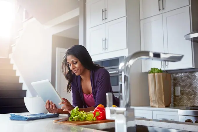 Its never been easier to stay healthy. a young woman using a digital tablet while preparing a healthy meal at home.