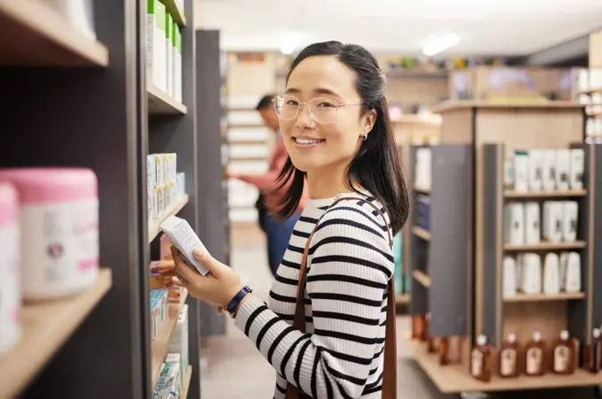 Portrait of happy woman, retail shopping and shelf in store for products, groceries and choice of brands. Asian female, customer and supermarket aisle for grocery, sales decision and consumer buying