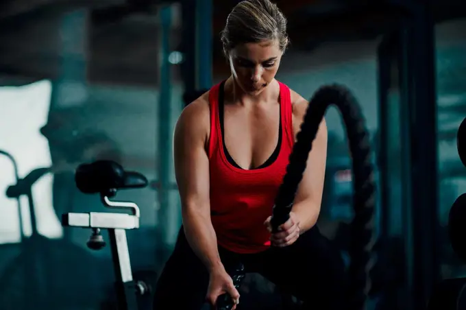 Ready for battle. an attractive young female athlete working out with battle ropes in the gym.