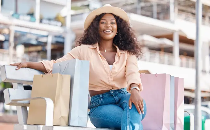 Black woman, retail shopping bag and outdoor bench break from travel buying, sales and summer market retail fashion promotions in San Francisco California. Happy portrait of wealthy customer spending