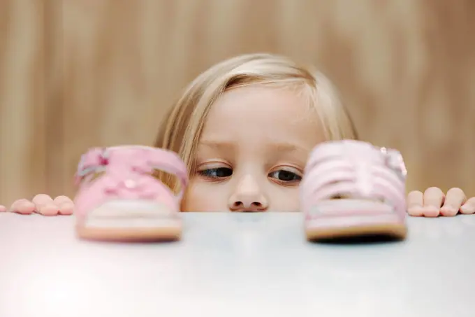 Kids, fashion and shoes with a girl choosing between footwear while shopping in a retail store. Children, cute and choice with a young female child deciding what shoe to buy for her home wardrobe