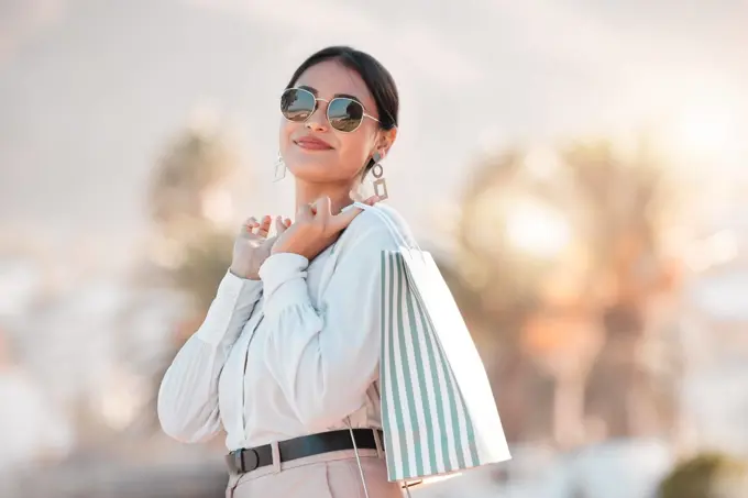 Retail shopping bag, urban woman and portrait travel for discount sales, market and outdoor sun in Dubai. Happy rich arab customer, consumer and wealthy person with sunglasses buying luxury fashion