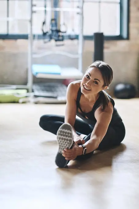 Portrait, smile and woman stretching, fitness and workout goal with balance, stress relief and happiness. Face, female person or athlete on the floor, stretch legs and training for wellness or health