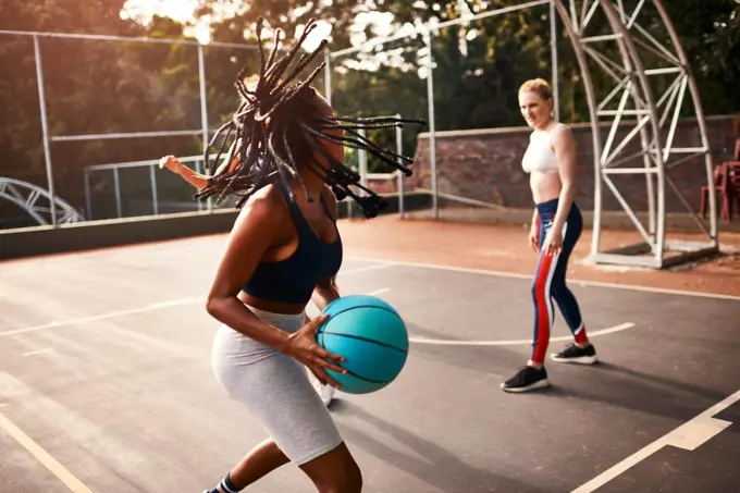 Can I score from here. a diverse group of sportswomen playing a competitive game of basketball together during the day.