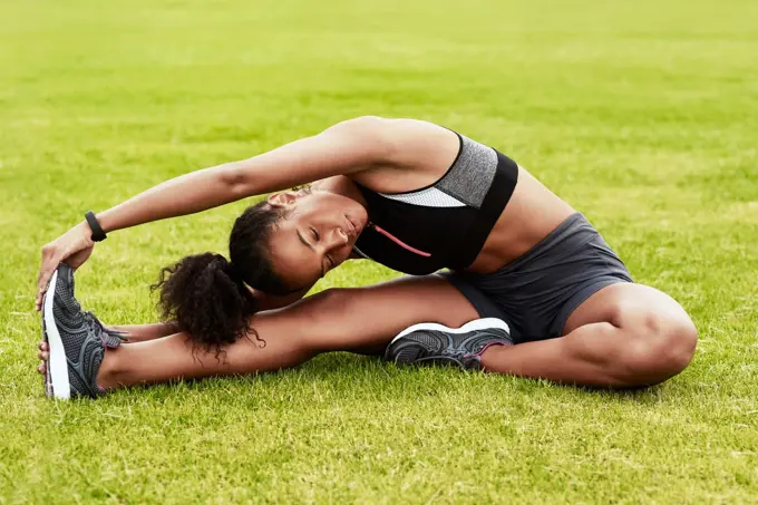 Youve gotta be flexible. Full length shot of an attractive young female athlete warming up at the track.