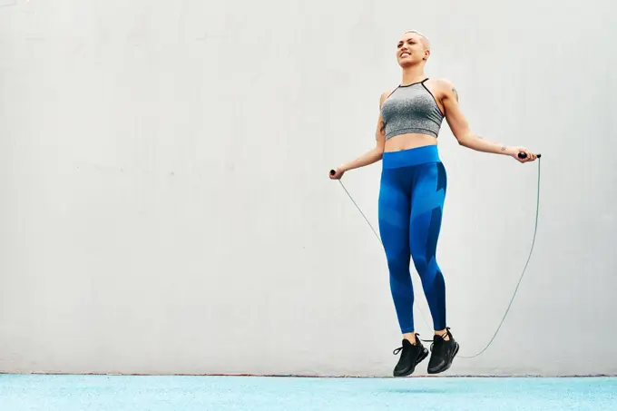 Jump, rope and woman skipping against space in stadium for sports, workout practice and cardio. Performance, health and body with female athlete training on track for strong, mockup and exercise