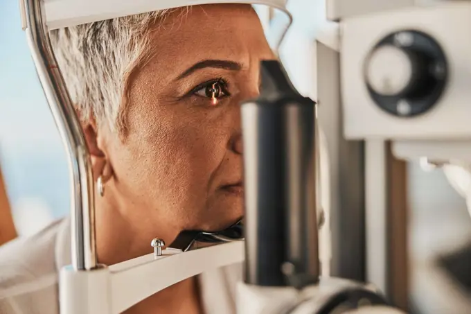 Medical, ophthalmology and eye test by patient senior woman with medical insurance using slit lamp. Mature, optometry and female doing vision or eyesight test in clinic using a machine