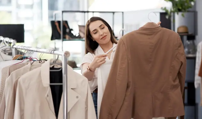 Shopping, retail and a woman customer in a mall boutique to buy trendy clothes for seasonal fashion. Search, store and sale with a young female consumer in a shop, making a clothing purchase choice