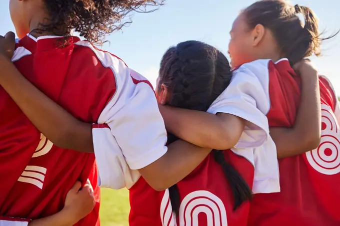 Girl, soccer group and back with huddle on field for match, contest or game with team building support. Female kids, football player children and hug for solidarity, diversity or motivation on pitch