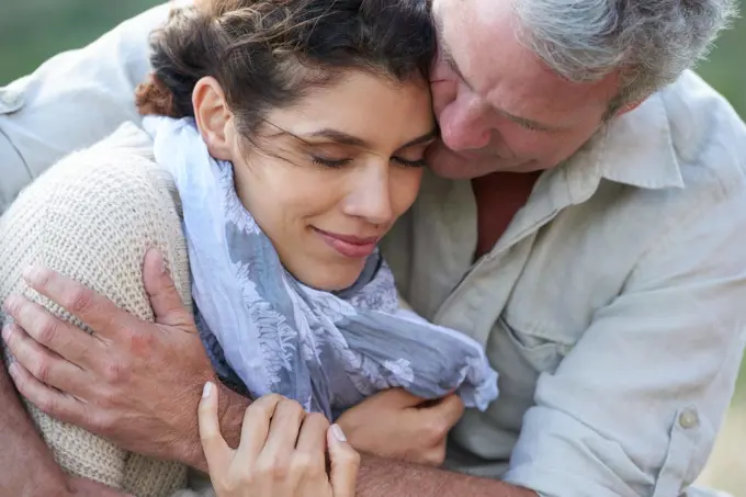 She appreciates his support and love. A loving couple hugging each other affectionately outdoors.