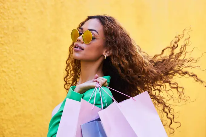 Wealth, posh and portrait of a woman with shopping bags for fashion, luxury sale and discount. Elegant, retail and rich girl in the city to shop, buying clothes and fashionable clothing on a wall