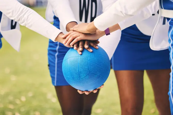 Sports, netball and team in a huddle with a ball for game strategy planning, motivation or pride. Fitness, diversity and female athletes with a stack of hands for collaboration on field before match.