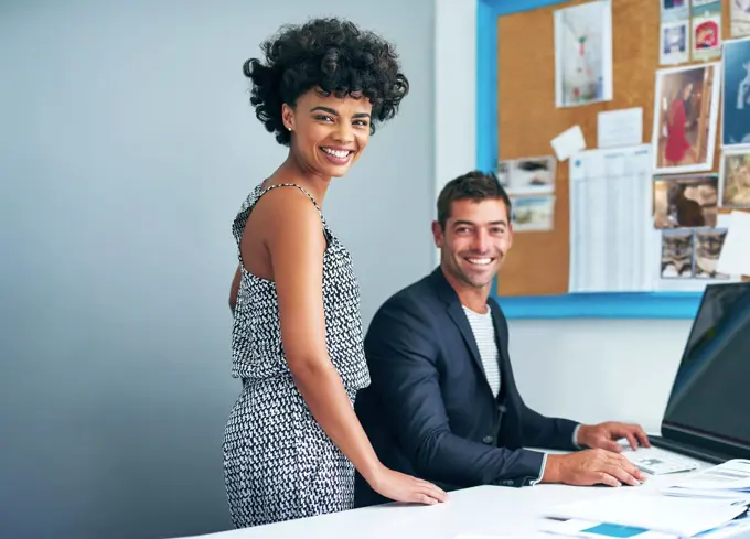 Success is smiling on them. Portrait of two coworkers working together at a computer in an office.