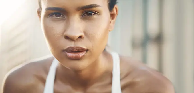 Face, portrait of a woman and fitness with a lens flare outdoors. Exercise or training, workout or motivation and closeup with African female athlete pose for health wellness or breathing