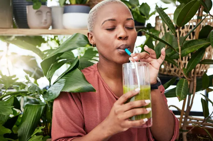 Nutrition, drinking and black girl with green smoothie for diet with plants for wellness or weightloss. Healthy, woman and enjoy a detox drink with vegetables for vitamins with supplement in home.