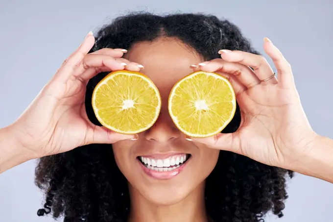 Woman, lemon eyes and skincare in studio for comic smile, health or nutrition for wellness by background. Girl, African model and fruits for diet, cleaning and cosmetic for beauty, self care or emoji