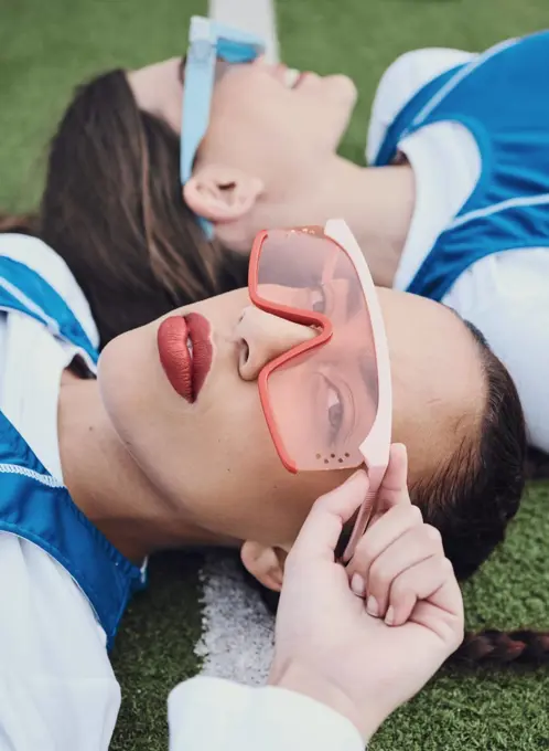 Women, portrait and athlete with fashion sunglasses for edgy styling, cosmetics and makeup in trendy eyewear. Athletes, sports field and sportswear on ground, teammates and cool posing with friend