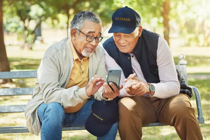 Elderly men, friends and phone in park, reading and army memory with thinking, relax and sunshine. Senior military veteran, smartphone social media and talk on bench, nostalgia and remember service