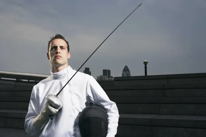 Fencer holding sword outdoors portrait