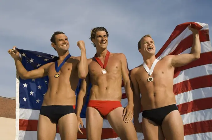 Victorious male athletes cheering up while holding an American flag