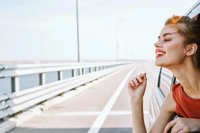 cheerful woman peeking out of the car window trip road travel