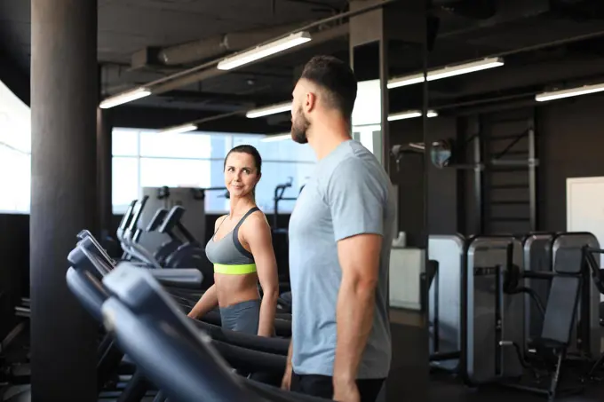 Healthy sport couple running on a treadmill in a sport gym.