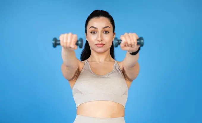 A healthy-looking young woman is training with dumbbells