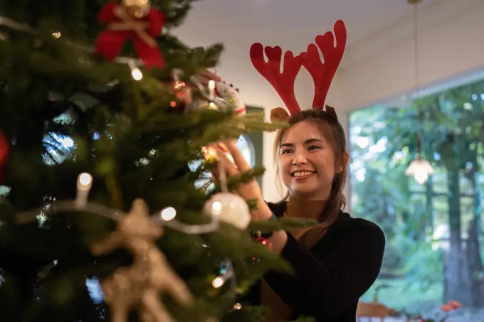 Young Asian woman decorate for Christmas at home. Family celebrate and Happy new year at home