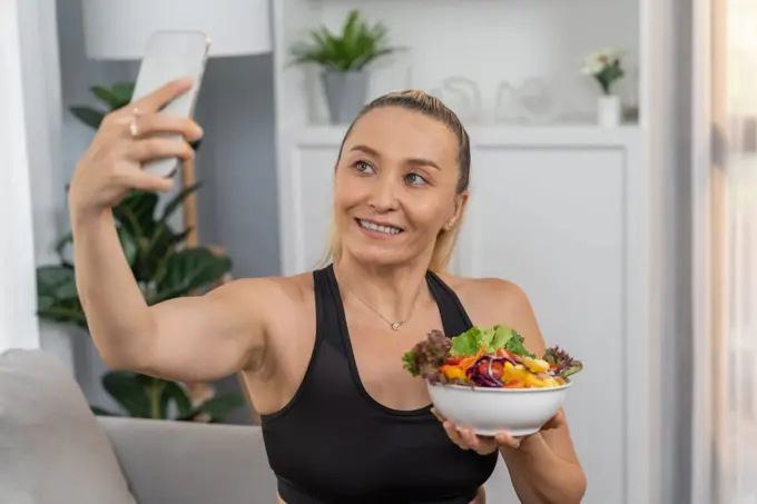 Healthy senior woman in sportswear taking selfie with vegan food. Clout