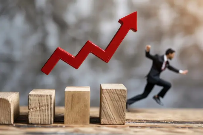 A man is running up a wooden staircase with a red arrow pointing upwards. Concept of progress and achievement, as the man is reaching for a higher goal