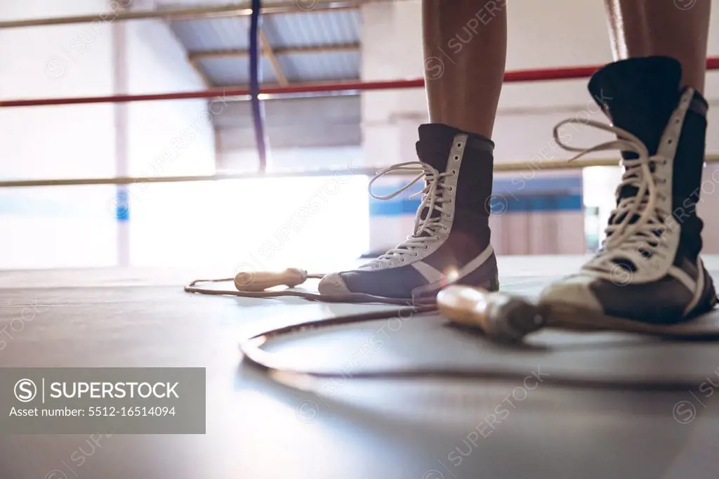 Low section of female boxer standing in boxing ring at fitness center. Strong female fighter in boxing gym training hard.