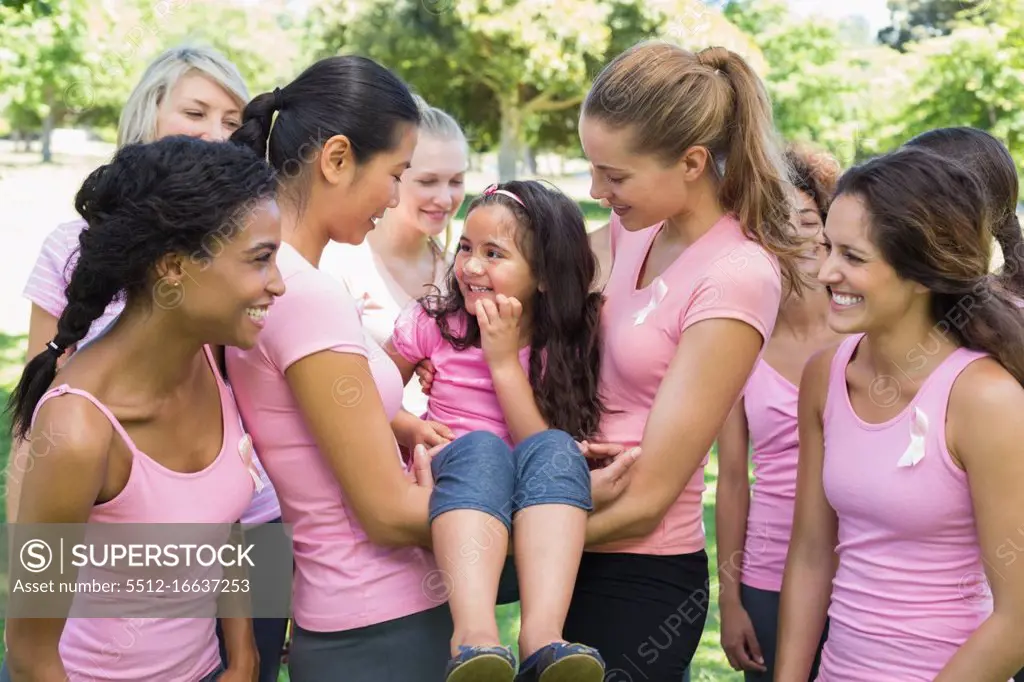 Happy female volunteers carrying girl during breast cancer campaign at park