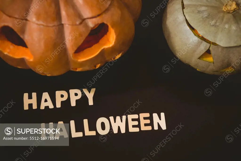 High angle view of happy Halloween text by jack o lanterns over black background