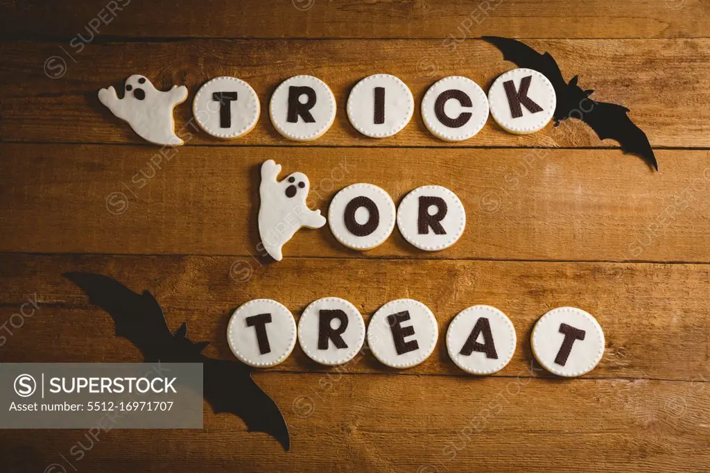 High angle view of cookies with trick or treat text by spooky decorations on table