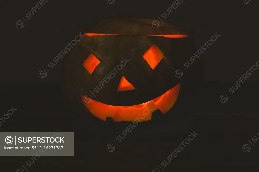 Close up of jack o lantern glowing in darkroom