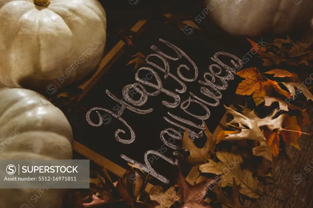 High angle view of happy Halloween text on slate with pumpkins and autumn leaves