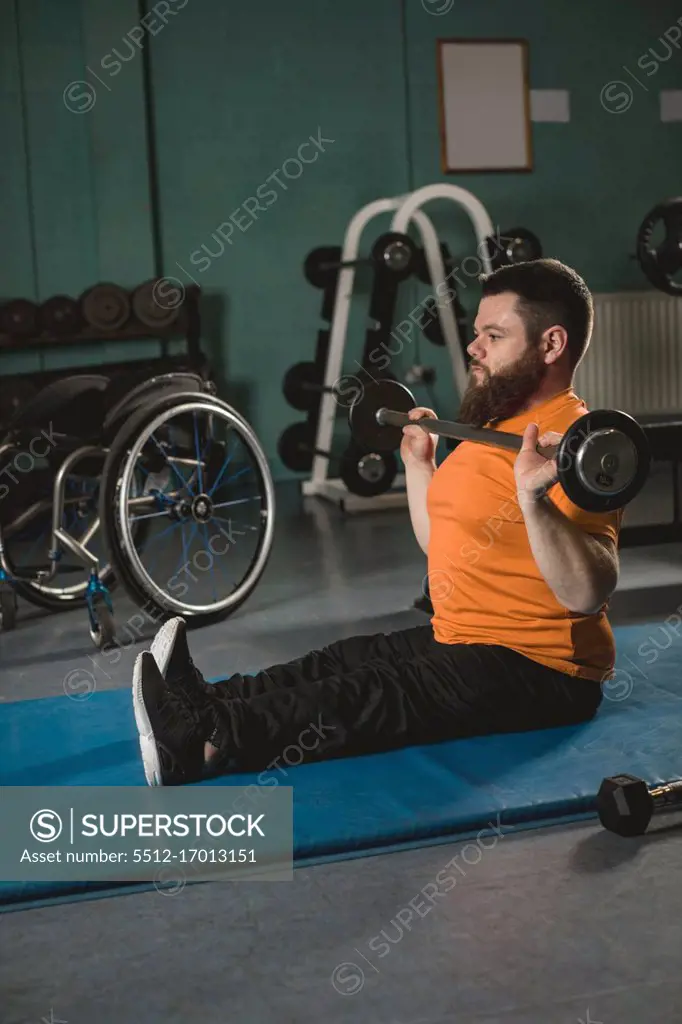 Handicapped man exercising with barbell in gym
