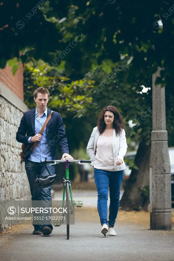 Young business colleagues walking on sidewalk in city