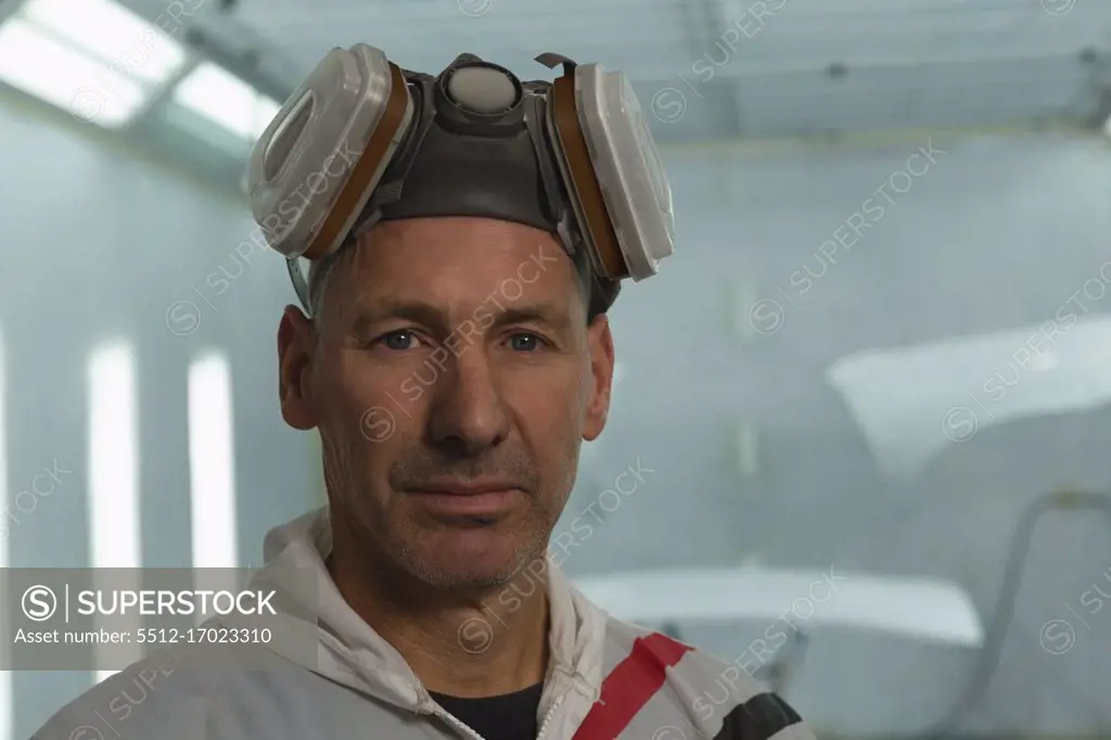 Close-up of mechanic looking at camera in garage