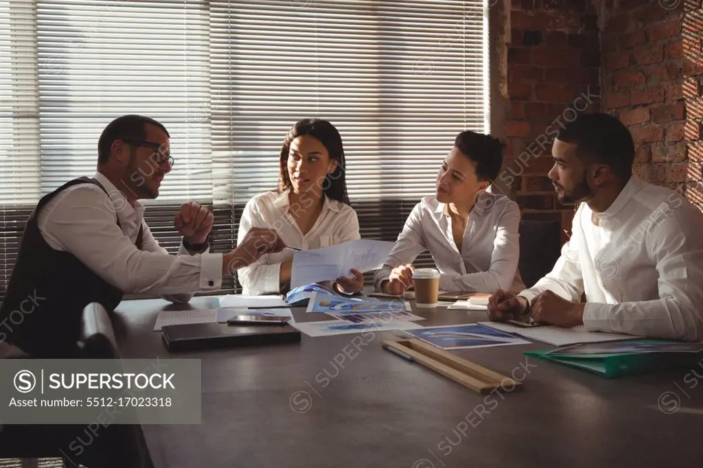 Executives discussing over document in conference room in office