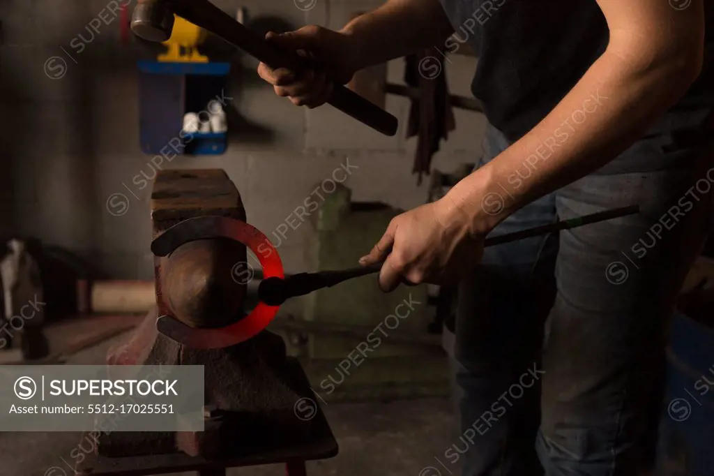 Mid section of female metalsmith molding horseshoe in factory