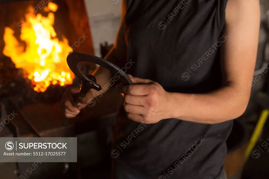 Mid section of female metalsmith molding horseshoe in factory