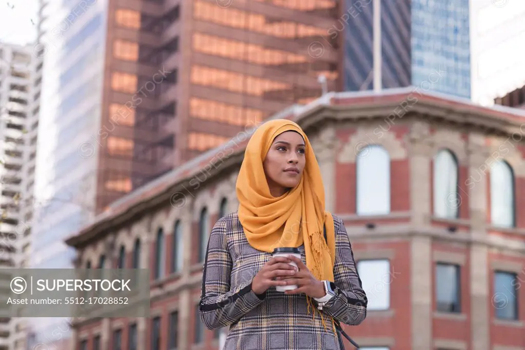 Thoughtful hijab woman having coffee in city